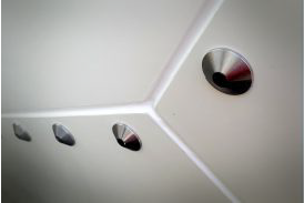Close-up of a white radome-like geometric surface with circular metallic fixtures embedded, creating a modern abstract design.