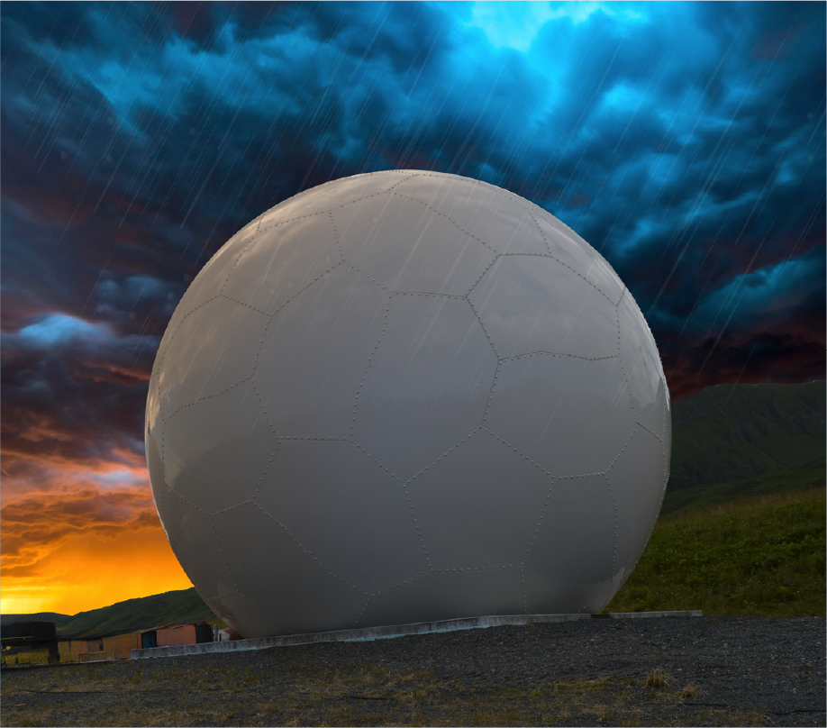 A large white geodesic dome radar, used in various applications, stands on grassy terrain under a dramatic sky filled with dark storm clouds, rainfall, and a vibrant orange sunset on the horizon.