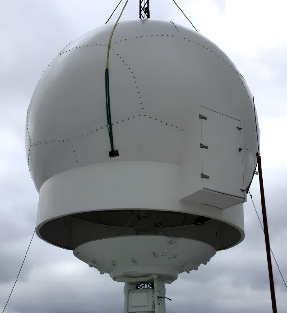 A large, white spherical radar dome with visible seams and a small access door is mounted on a platform against a cloudy sky. Several cables support the dome, which features advanced Infinite RCS technology for minimal radar cross-section.